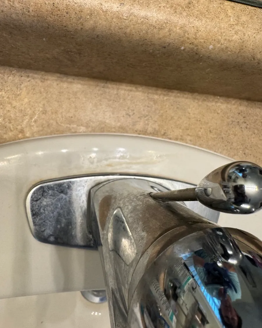 Bathroom faucet with a white limescale crust around its base