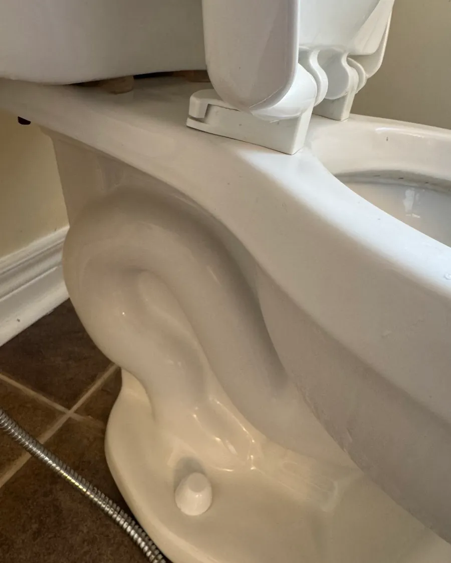 The base of the toilet and the floor tiles around it, clean