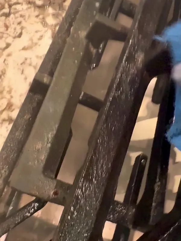 Gloved hand scrubbing a cast iron stovetop grate