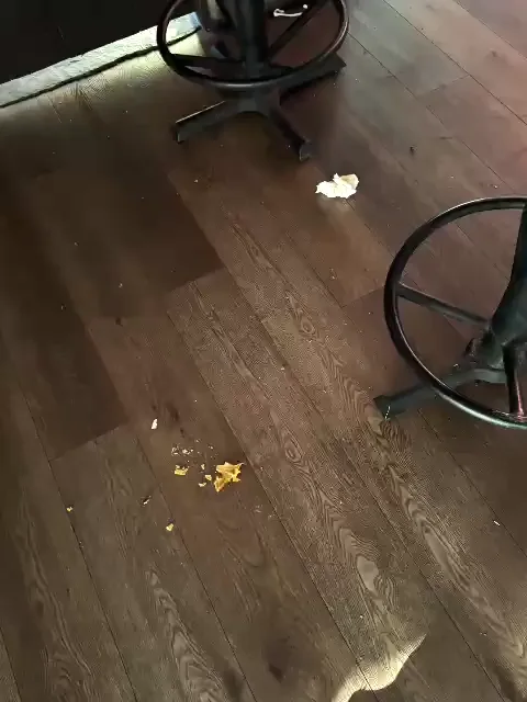 Napkin and crumbs on a wood floor next to a bar stool