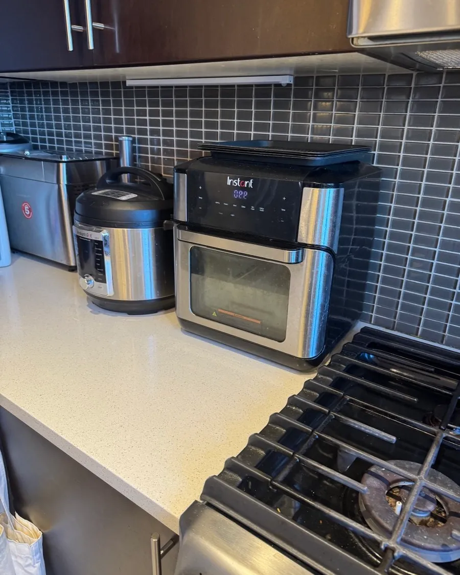 White kitchen counter with three small appliances next to a gas stove