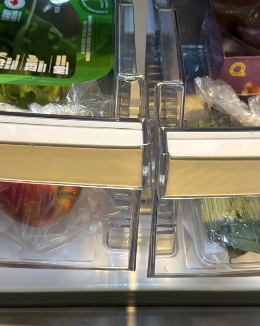 Crisper drawers seen from the front with lettuce, apples and greens inside