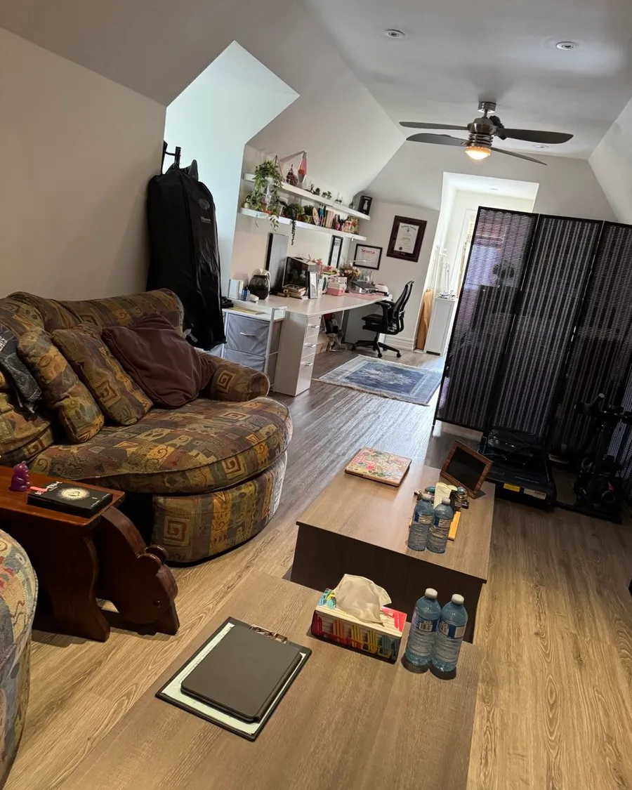 The same living room from the sofa, with low tables and a desk at the far end
