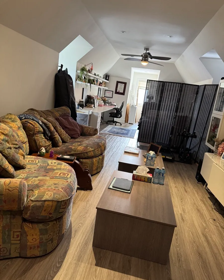 Tidy living room under a sloped ceiling with two sofas, a long coffee table and a wood floor