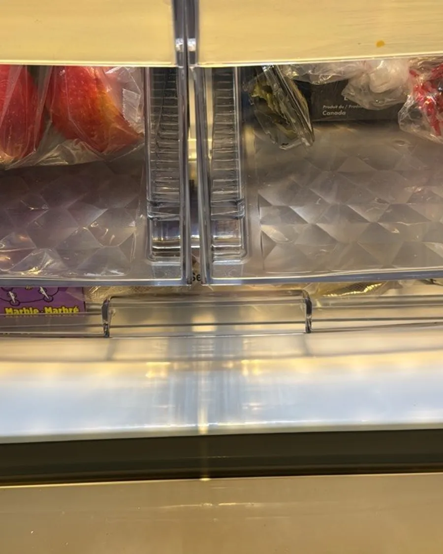 Two crisper drawers with apples, a cucumber and other produce