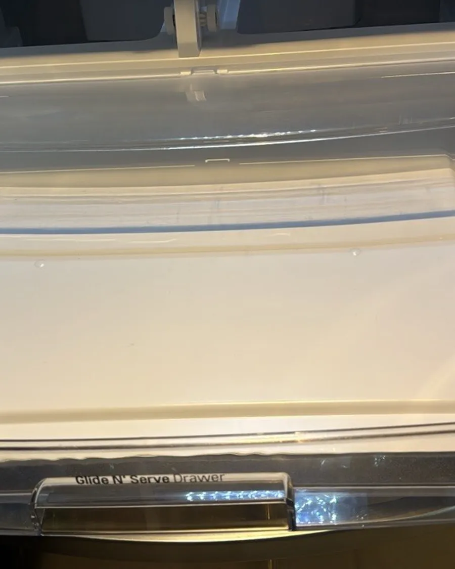 Wide fridge drawer pulled out, empty, with a clear front