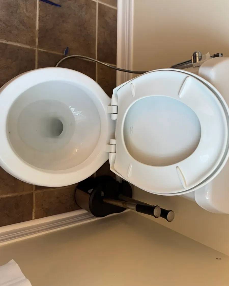 Toilet seen from above with the lid open, on brown floor tile